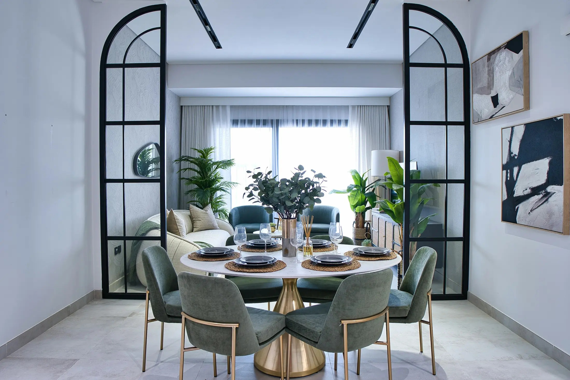 Dubai apartment dining room with arched black screens, green velvet chairs and brushed brass details
