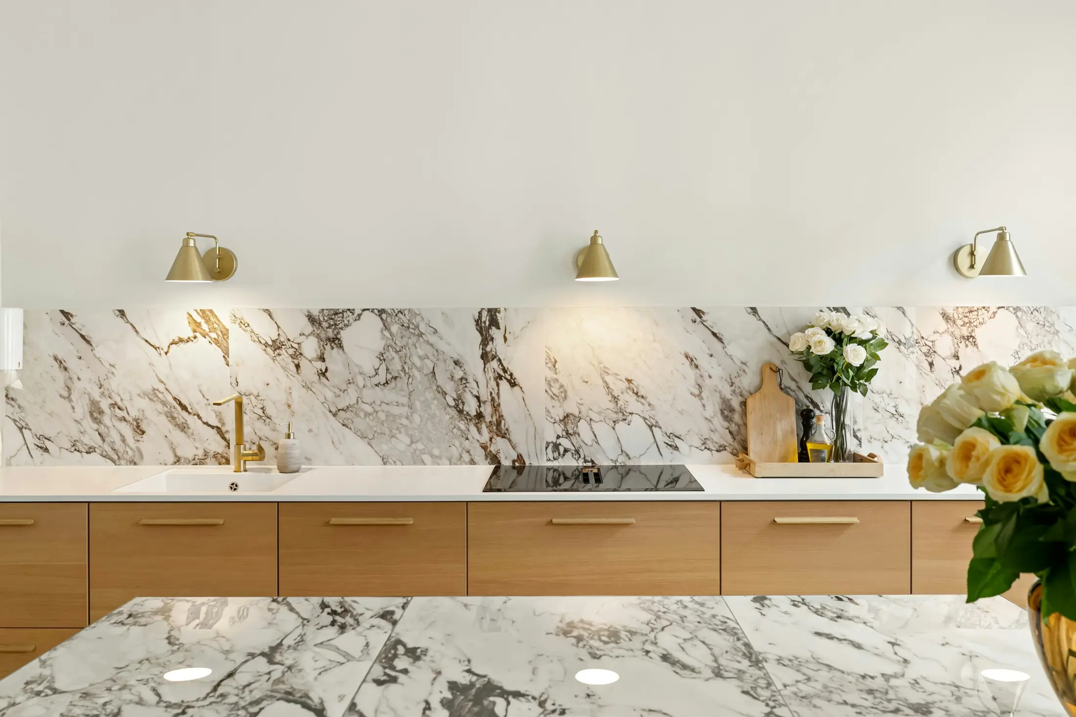 Close view of richly veined marble, warm oak cabinetry and brushed brass fittings