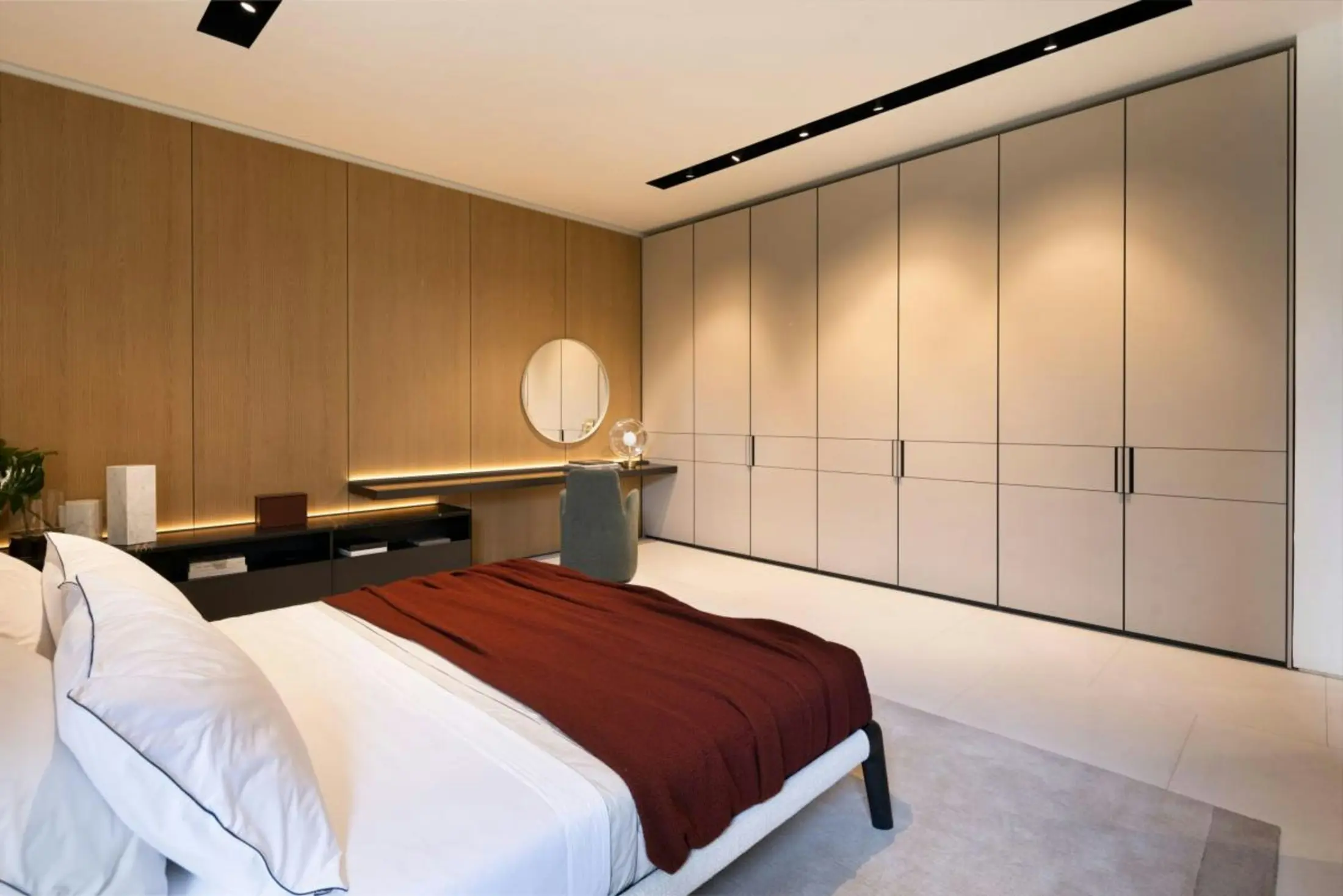 Tailored private suite with full-height wardrobes, warm oak panelling and integrated lighting